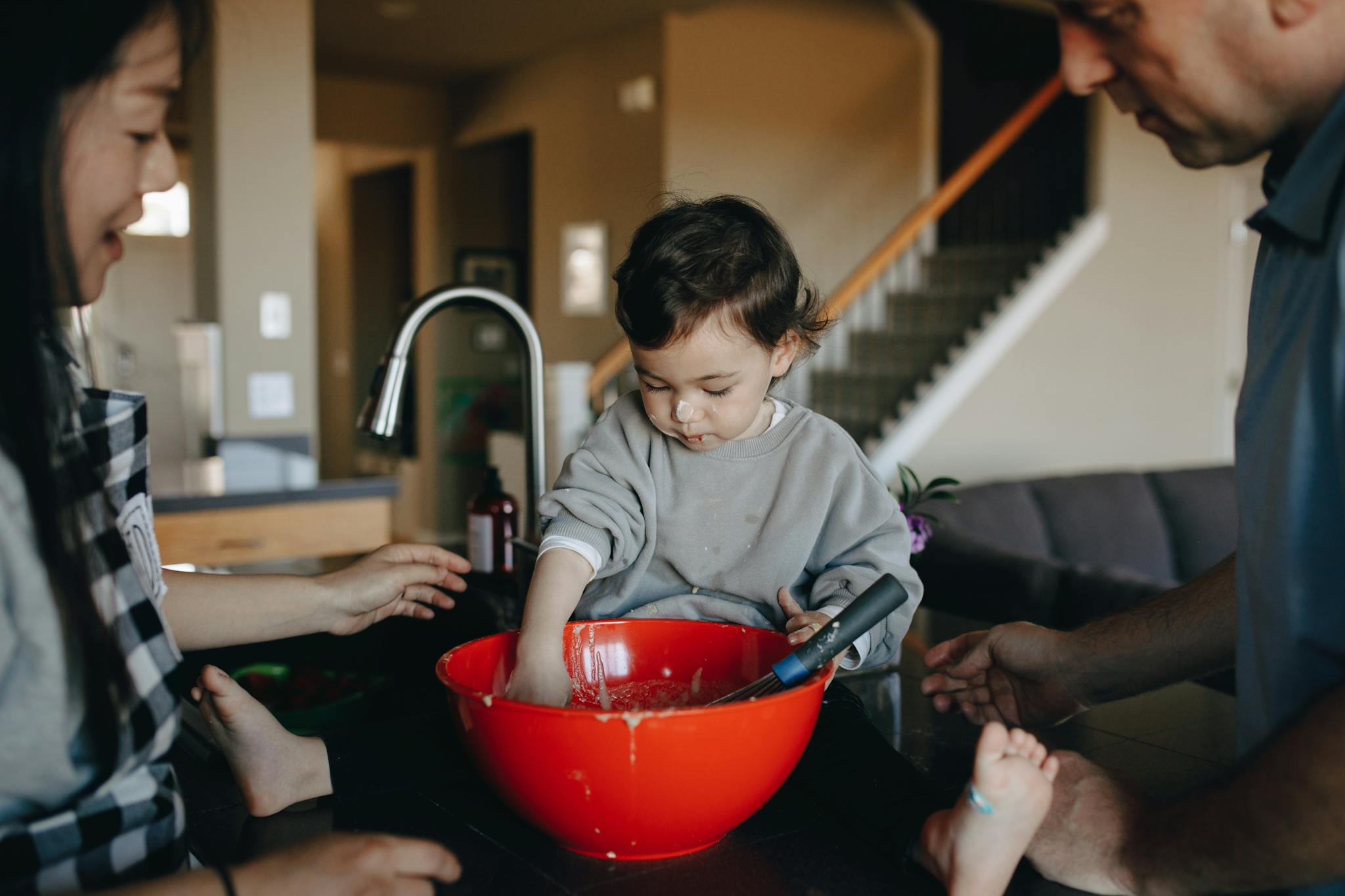 A family bonding moment as parents and a child prepare food in the kitchen.